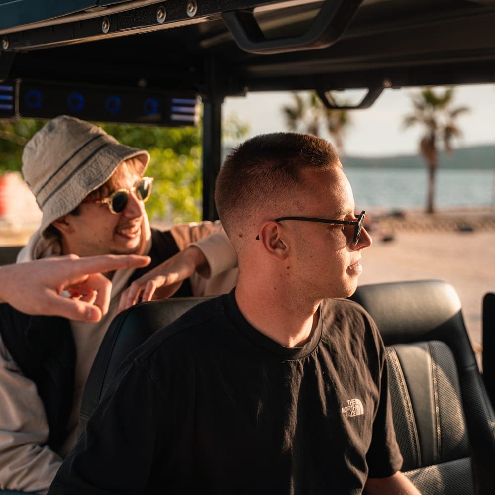 Guide and guest enjoying golden-hour views from a Hidden Split Tours electric vehicle by the coast